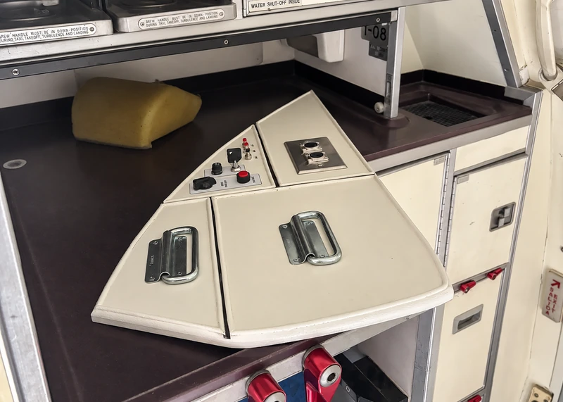 Fabricated cream aircraft galley panel with recessed metal handles and switches