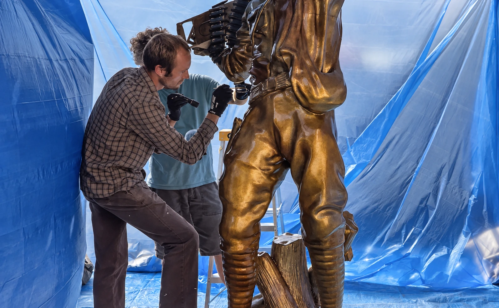 Scenic artists applying a bronze finish to a large sculptural figure