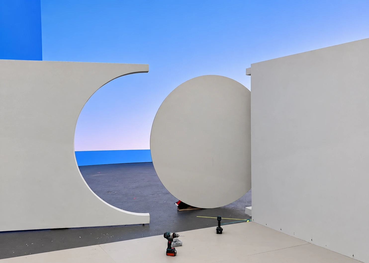 White curved set walls and a circular panel under construction for Snooze, with tools visible
