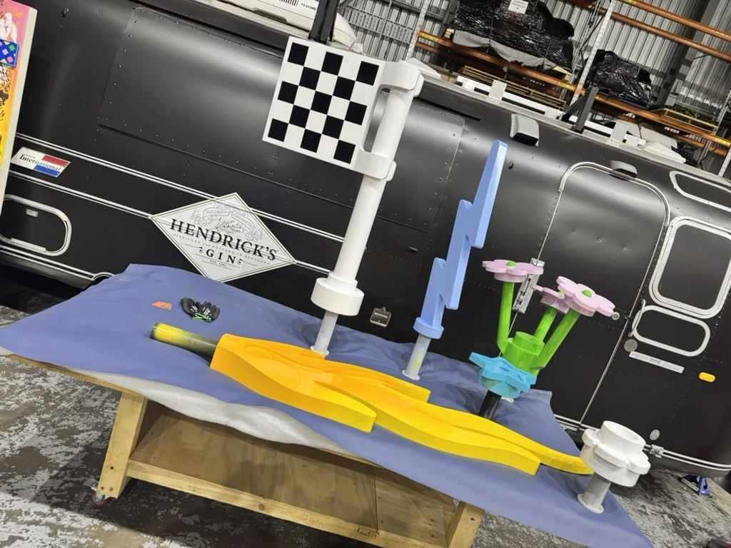 Flag, lightning, flowers and flame components arranged together on a workshop bench