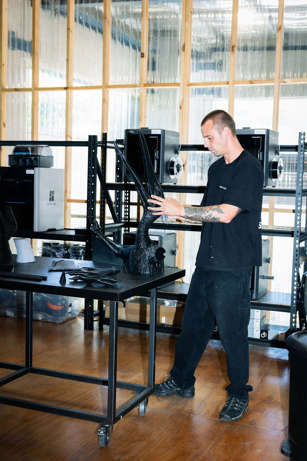 A Trade Arts maker inspecting a sculptural piece beside the workshop’s 3D printers