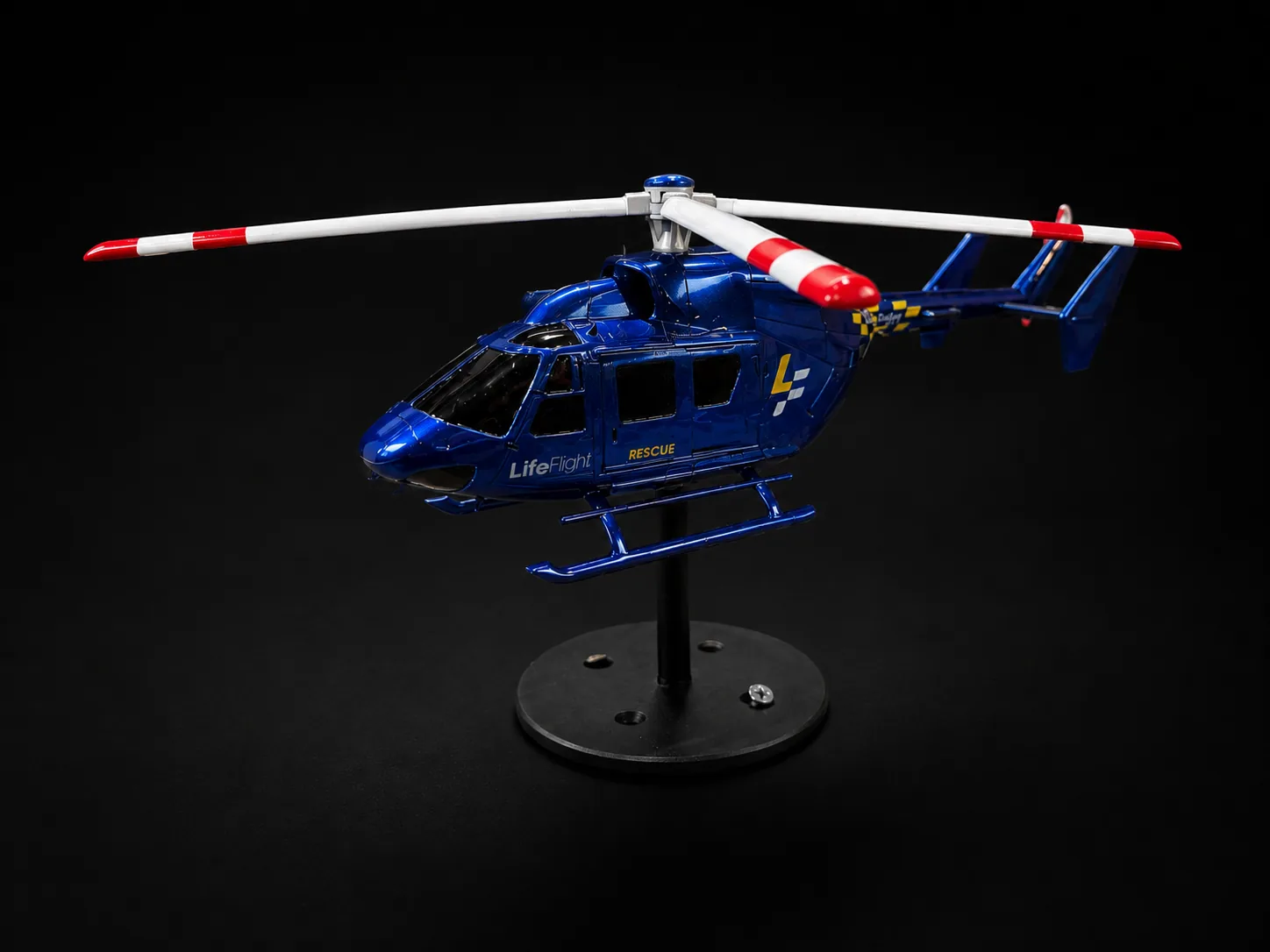 Blue rescue helicopter scale model mounted on a black display stand
